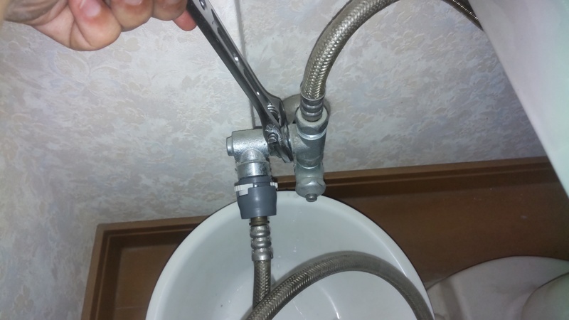ウォシュレットのホースを水栓から外している様子